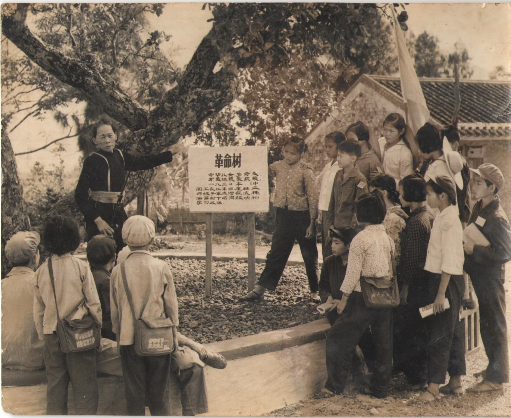 19世纪60、70年代，红色娘子军老战士黄盛蓉在操练场的革命树下，给小学生讲革命故事。